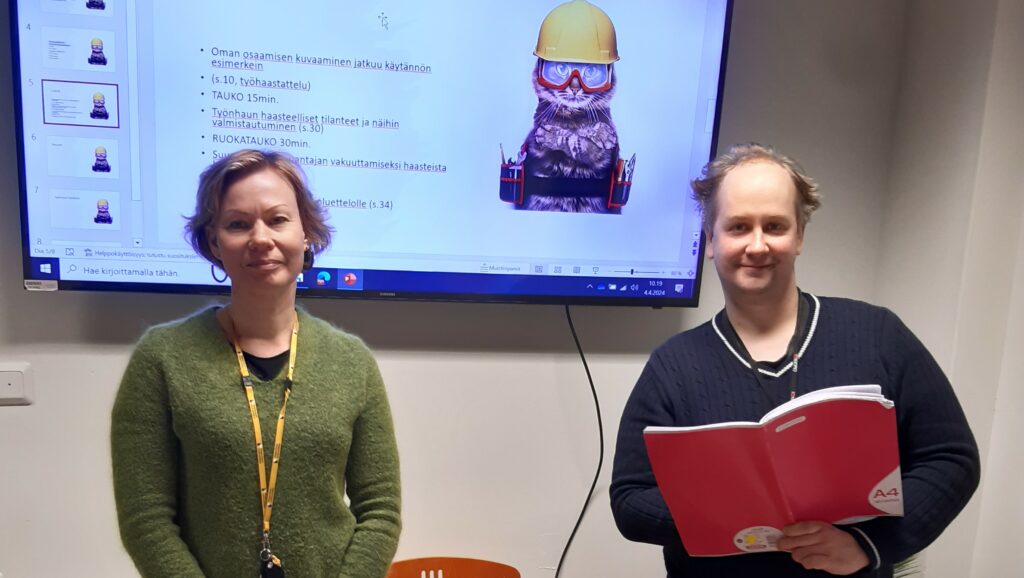Valmentajat hymyilevät kameralle palaverihuoneessa.