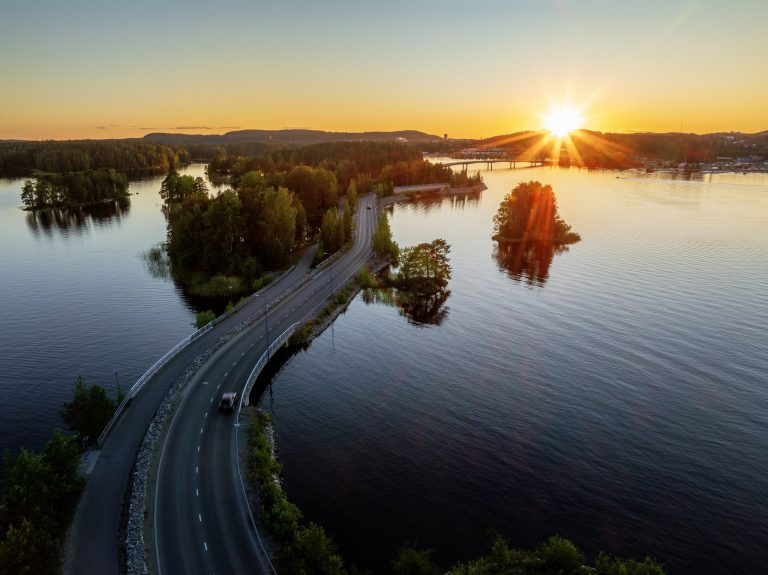 Aurinko laskee taivaanrantaan värjäten taustan keltaiseksi. Etualalla Saaristokatu ja Kallavettä.