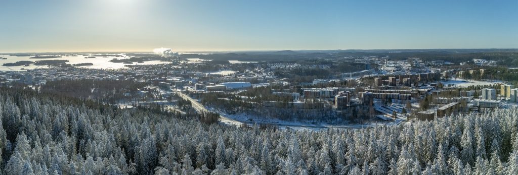 Talvinen maisema sinistä taivasta vasten, edessä lumisia puita.