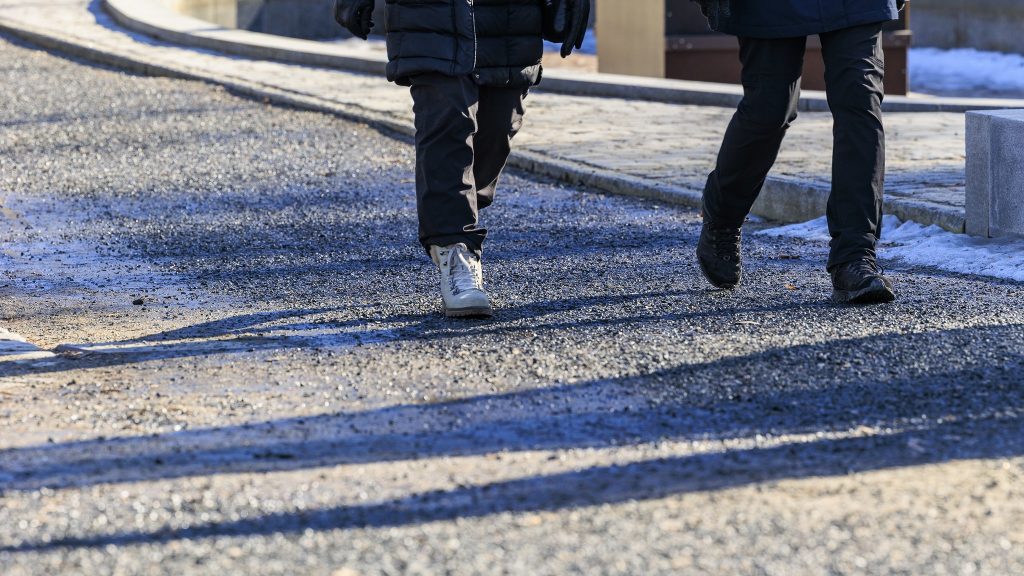 Hiekkainen jalankulkuväylä, kahden henkilön jalat.