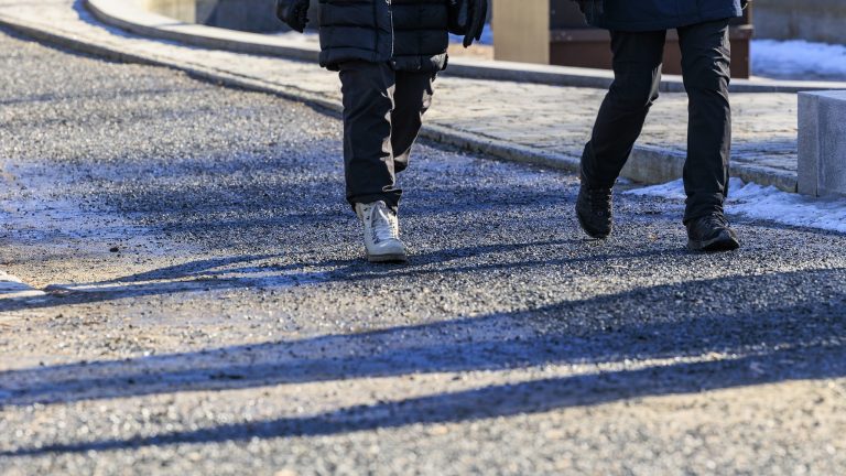 Hiekkainen jalankulkuväylä, kahden henkilön jalat.