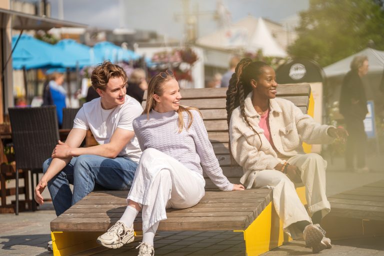 Kolme nuorta istuu torilla kesäpäivänä.