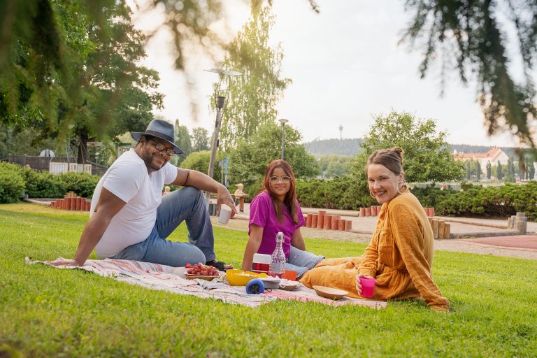 Kolme henkilöä piknikillä kesäpäivänä.