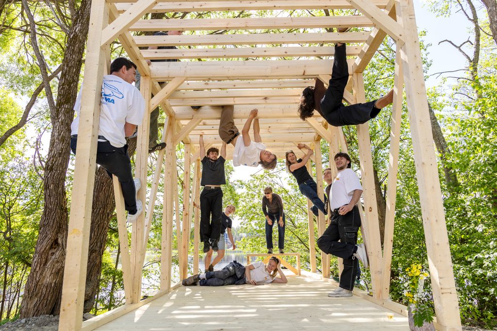 Opiskelijoita kiipeilee puurakenteissa luonnon keskellä.