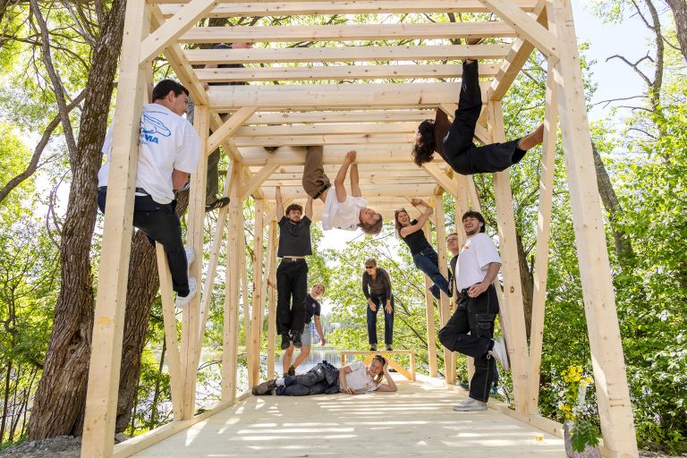 Opiskelijoita kiipeilee puurakenteissa luonnon keskellä.