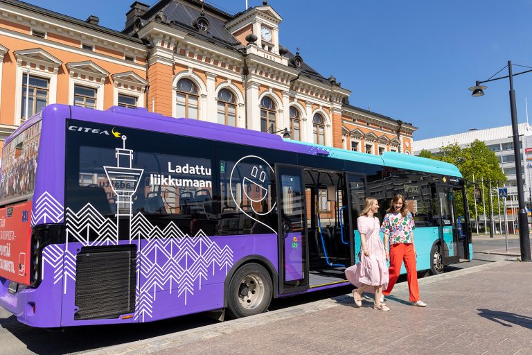 Kaksi henkilöä nousee sähköbussista.