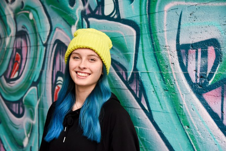 Tyttö graffitiseinän edessä.