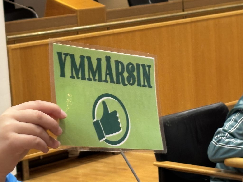 Lapsen kädessä vihreällä pohjalla oleva lappu, jossa lukee "ymmärsin" ja on peukalo ylöspäin