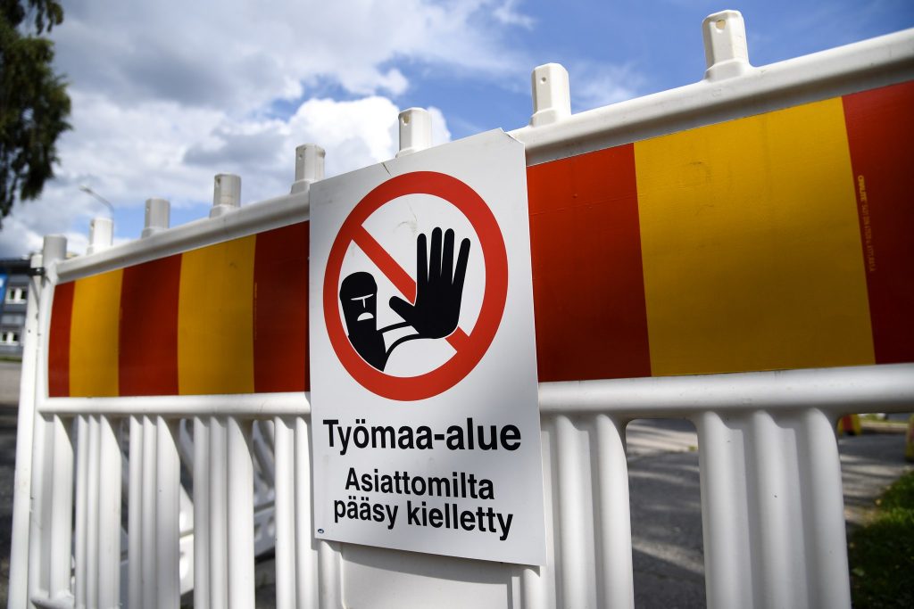 Keltapunainen työmaa-aita sinistä taivasta vasten.