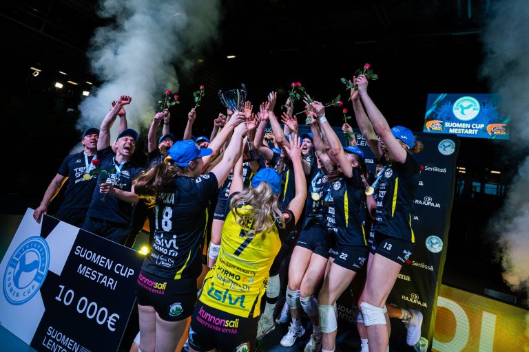 Naisten lentopallojoukkue juhlii voittoaan kädet ilmassa.