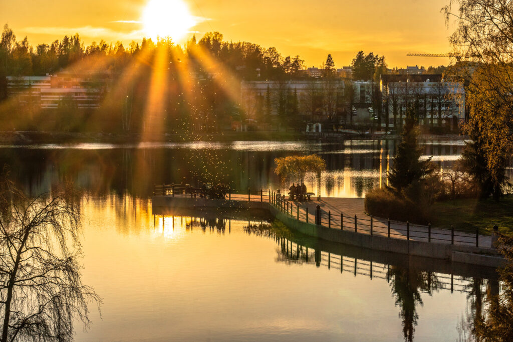 Valkeisenlampi auringonlaskun aikaan. Veteen heijastuu kaupunkimaisema.