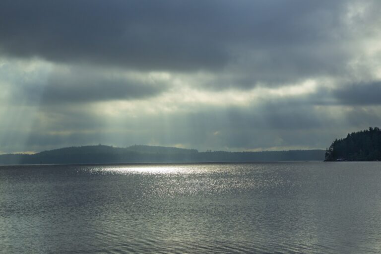 Järvi. Valo siilautuu pilvien välistä veteen.