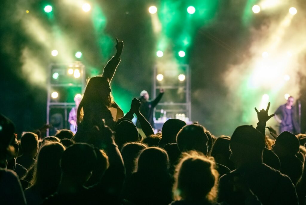 Ulkoilmakonsertti, edessä yleisö, takana konserttilava ja laservalot