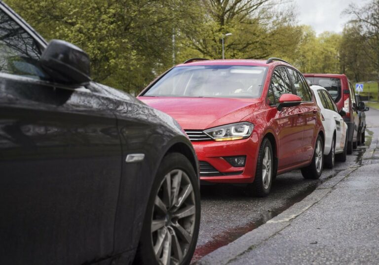kadun reunassa musta auto ja punainen auto pysäköitynä