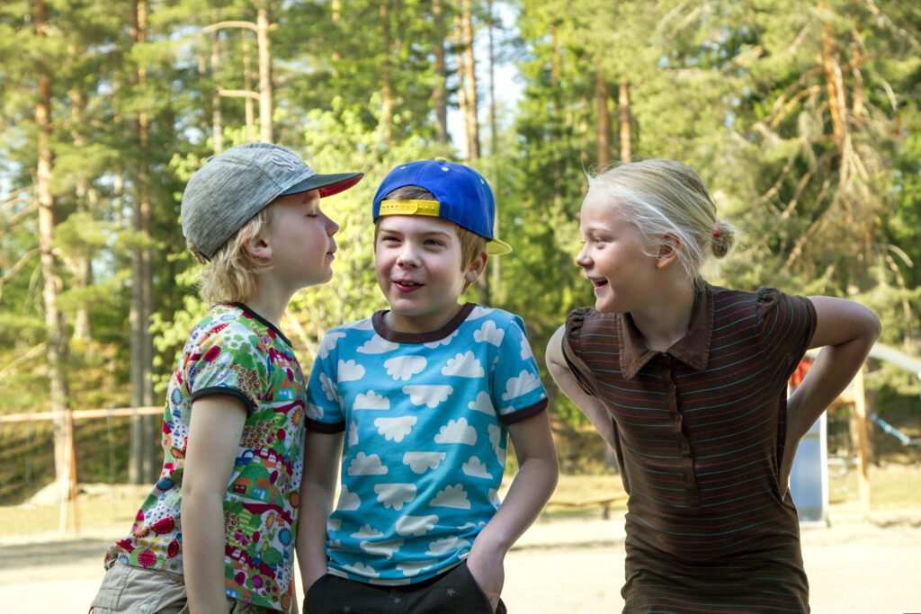 Kolme alakouluikäistä oppilasta ryhmässä ulkona.