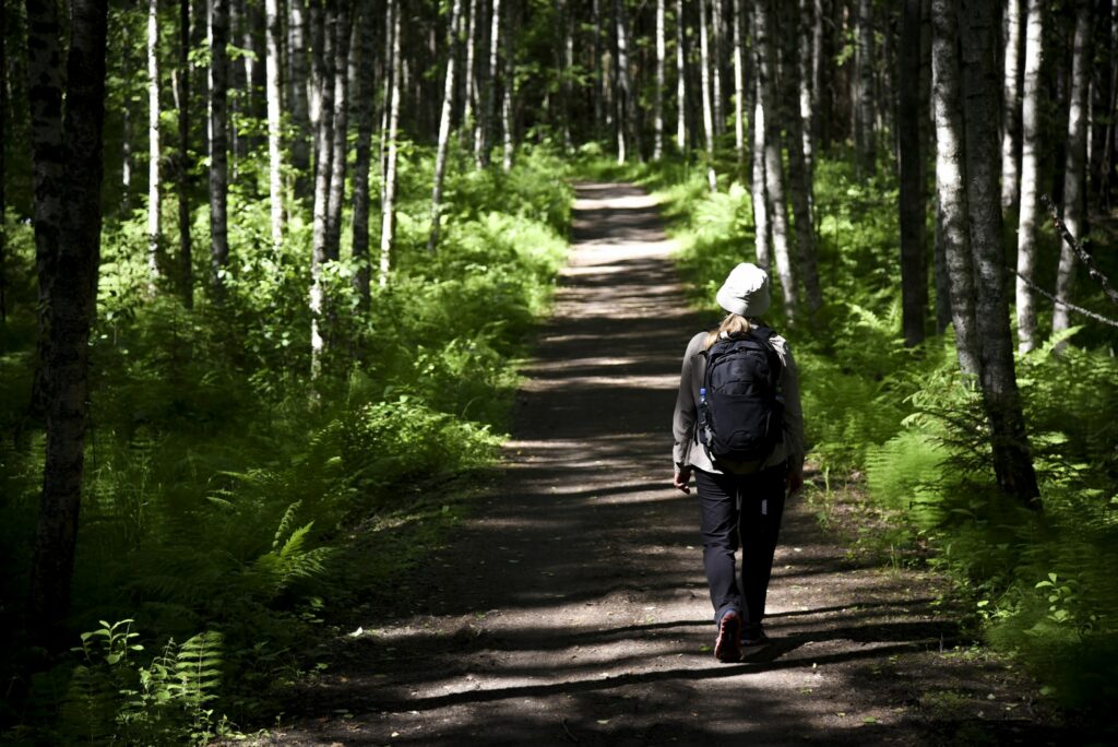 Luontopolku, jota pitkin naishenkilö kulkee kesäisessä metsässä