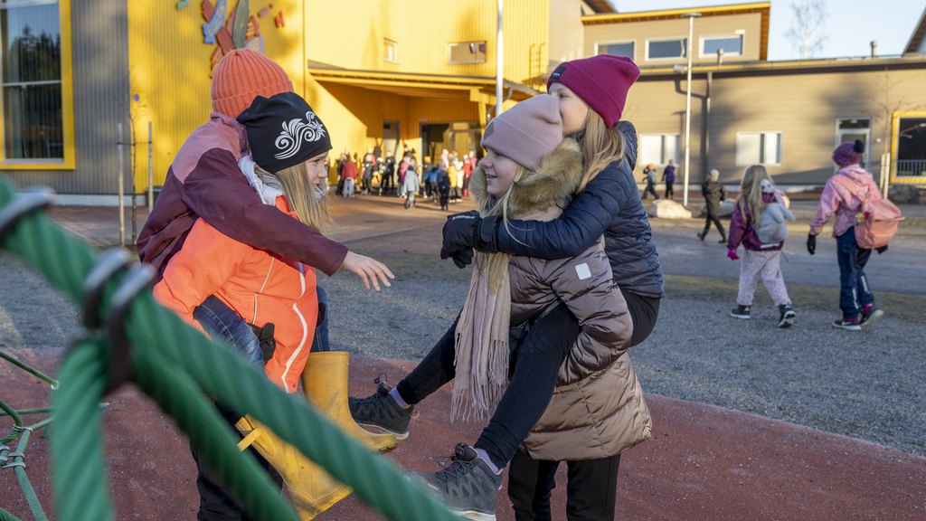 Kaksi alakouluikäistä oppilasta kahden alakouluikäisen oppilaan "reppuselässä" viettämässä välitunnilla.