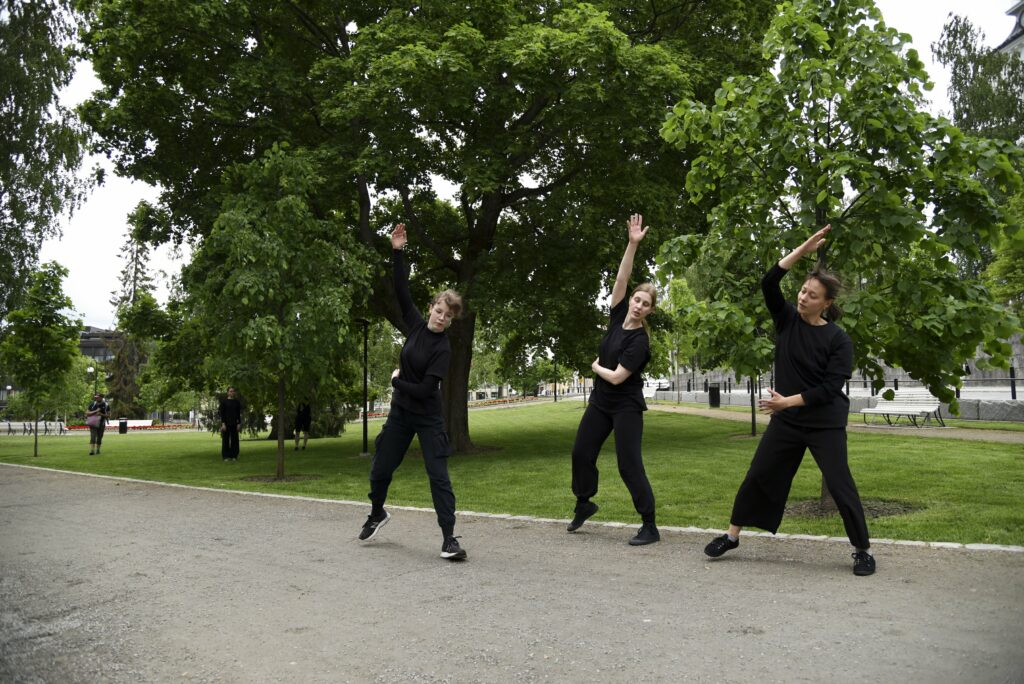 Kuopio Tanssii ja Soi esitys Snellmaninpuistossa, mustapukuiset tanssijat liikkuvat puiston läpi.