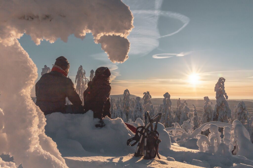 Lumikenkäilevä pariskuntaa istuu talvisessa maisemassa Tahkolla