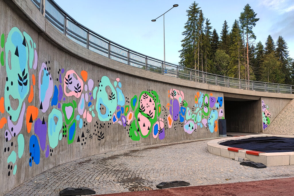 Graafinen ja värikäs muraali maalattuna sillan seinämään.