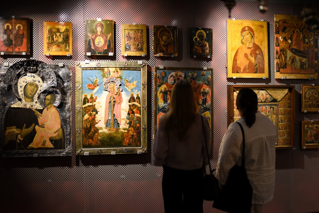 Kaksi ihmistä ortodoksisen kirkkomuseon näyttelytilassa katsomassa teoksia