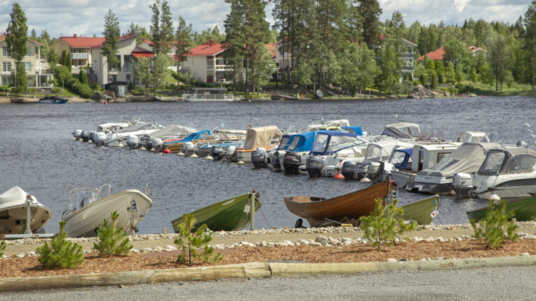Veneitä satamalaiturissa, taustalla omakotitaloja.