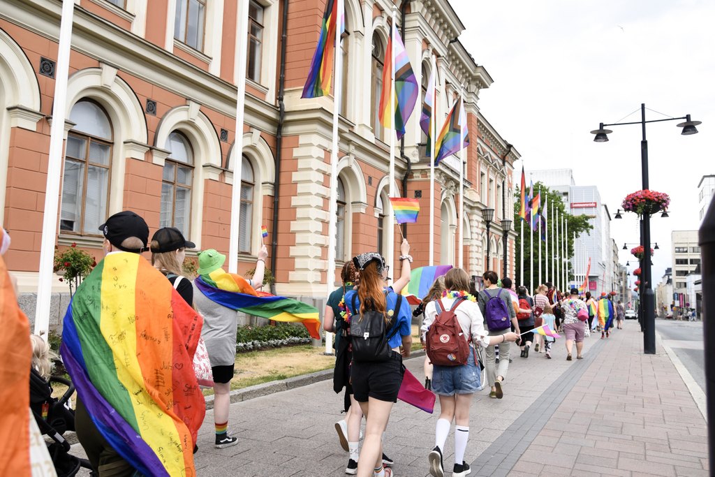 Ihmisiä kulkemassa Kuopion kaupungitalon ohi värikkäässä Pride-kulkueessa