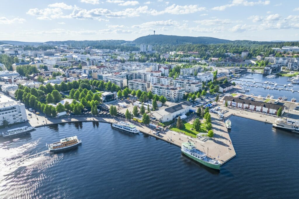 Kesäisessä ilmakuvassa Kuopion kaupunkia satamasta, taustalla Puijo.