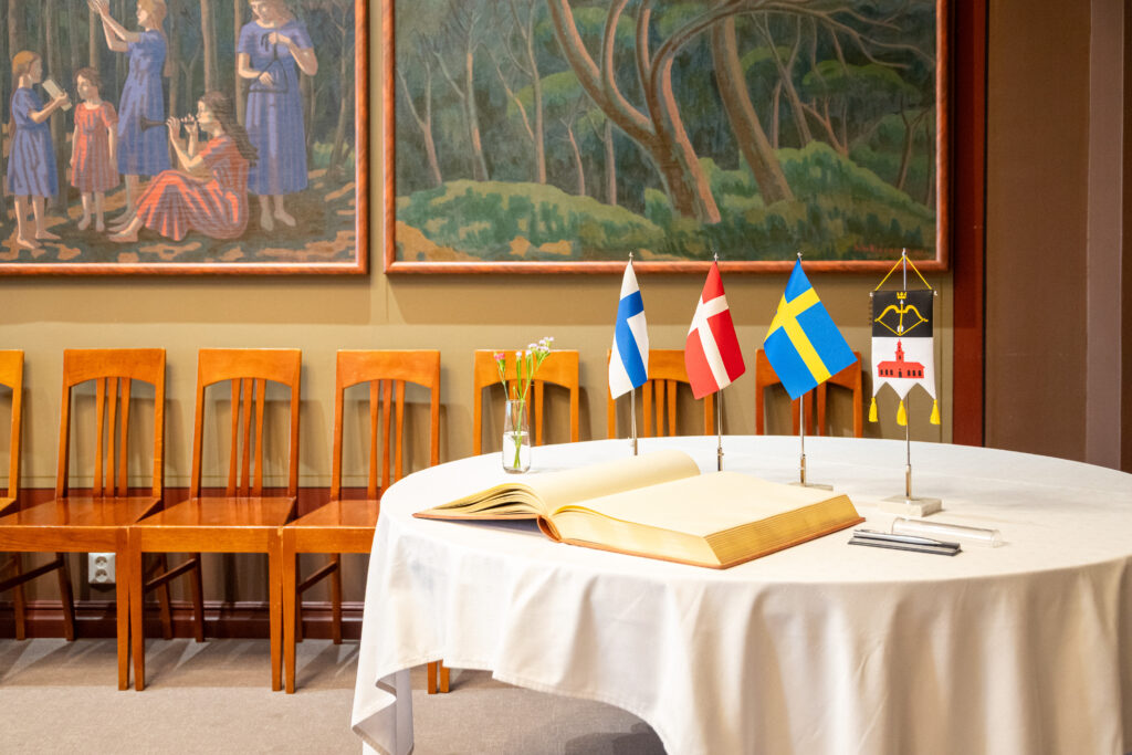 Pöytä, jonka päällä suomen, tanskan ja ruotsin lippu sekä Kuopion vaakuna